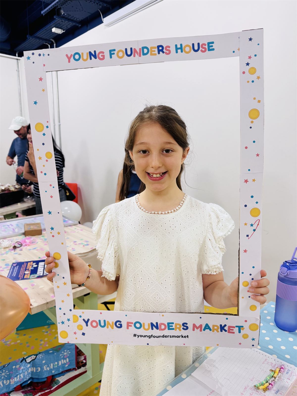 A child holding a Young Founders Market photo frame at the market